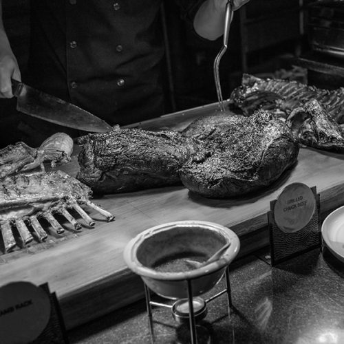 Meat carver carves roast beef for guests.